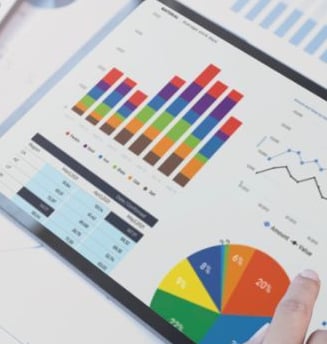 a person holding a tablet computer and pointing at a chart of graphs