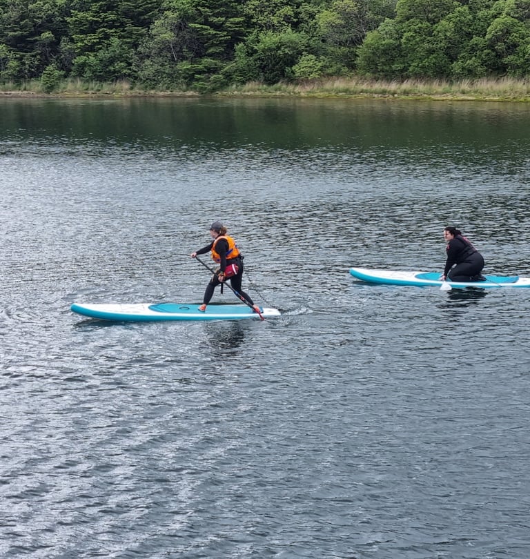 A stand up paddle board coach demonstrating to a student