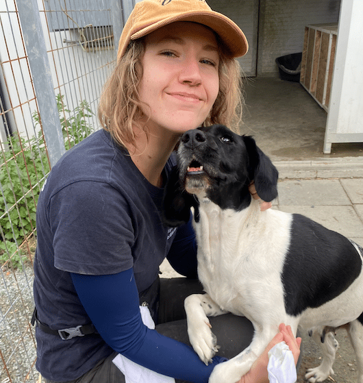a woman in a hat and a dog sitting on a stool