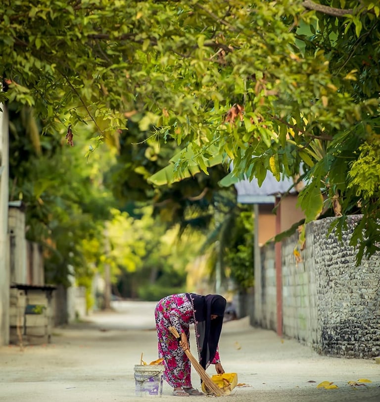 a woman in a pink dress is cleaning a sidewalk