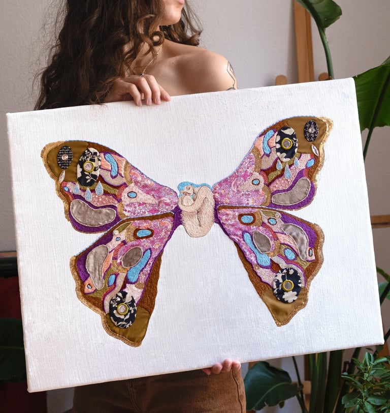 a woman holding an embroidery artwork of a butterfly