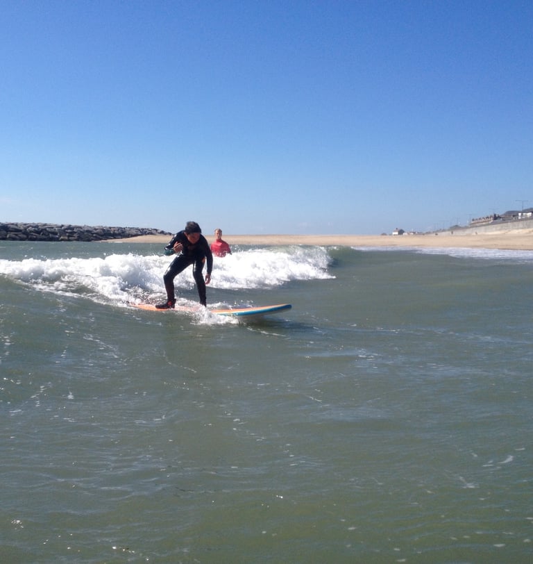 A young surfer riding a small unbroken wave in a surfing class