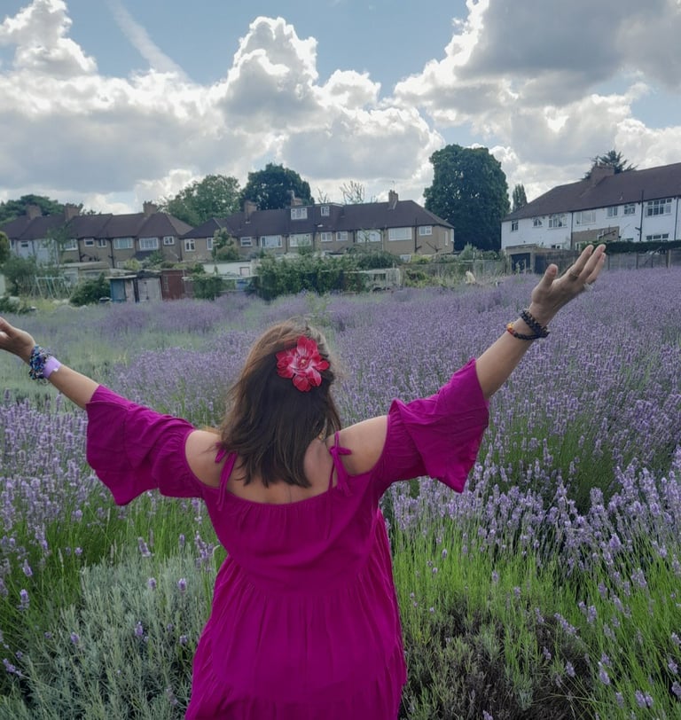 Image of the back of Sheila Cristina in a lavender field in London.  In the distance is houses. 