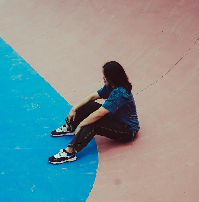 a person sitting on a skateboard on a ramp