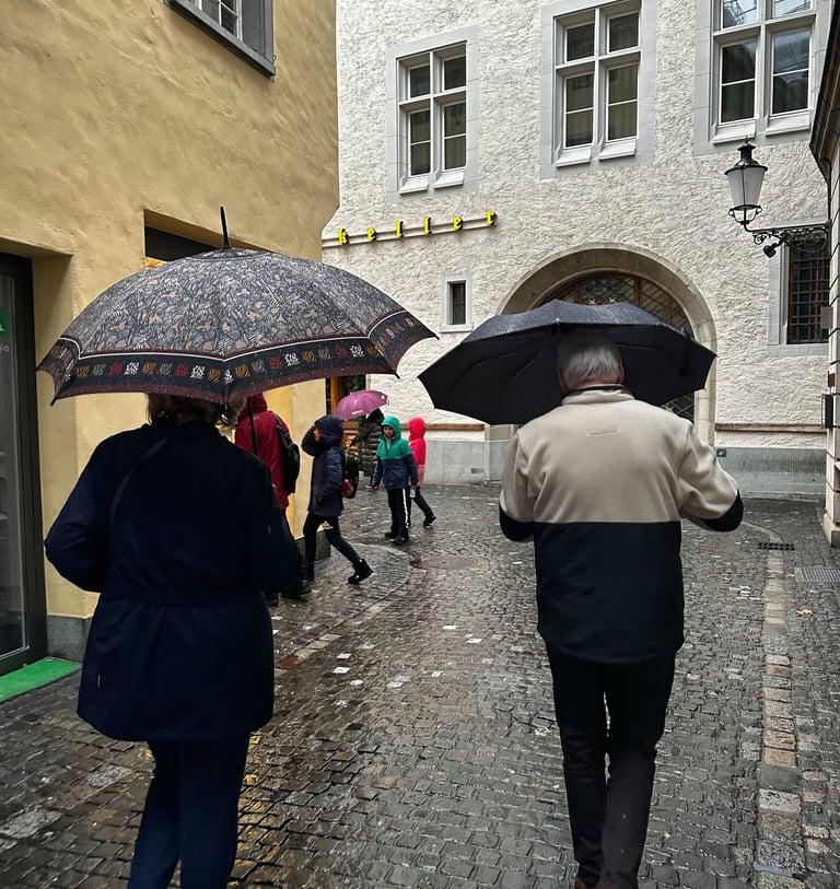 Rainy day in Switzerland, an older couple walk down the wet cobblestone roads together by LV