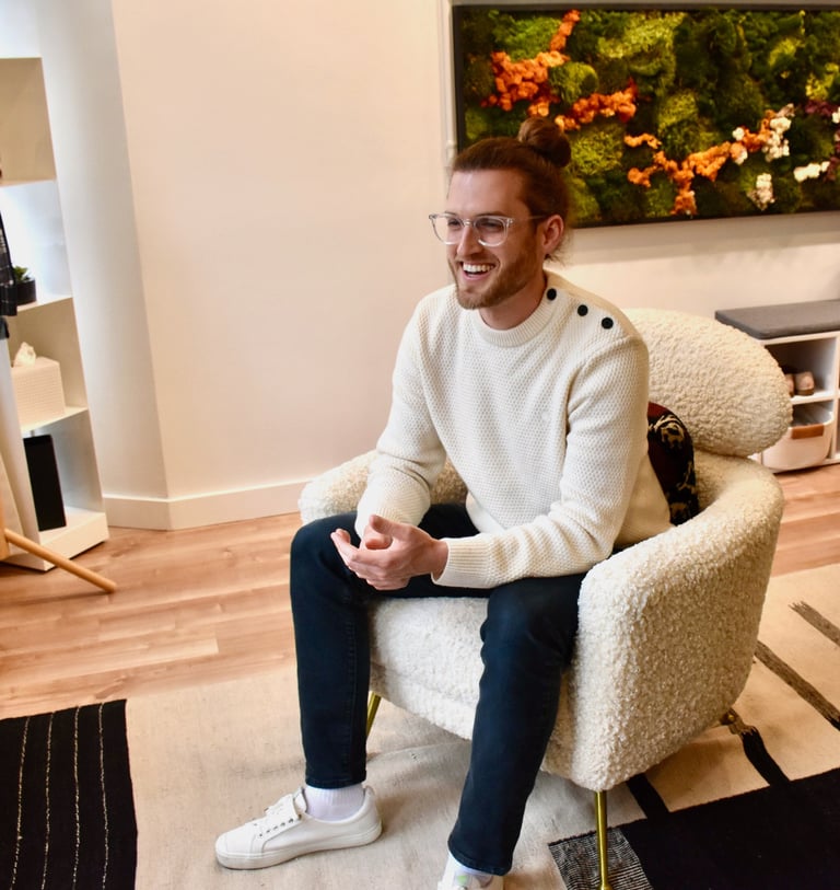 John in his office, sitting in white chair talking to someone