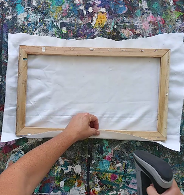 a person folding a piece of fabric over a frame