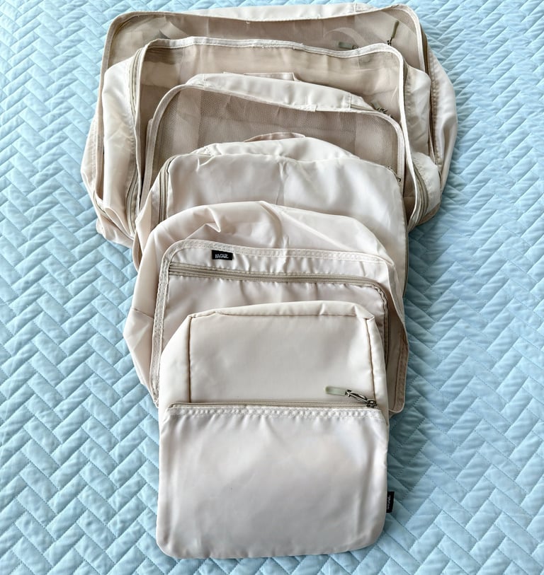 Cream colored packing cubes laid out for organizing clothing during travel