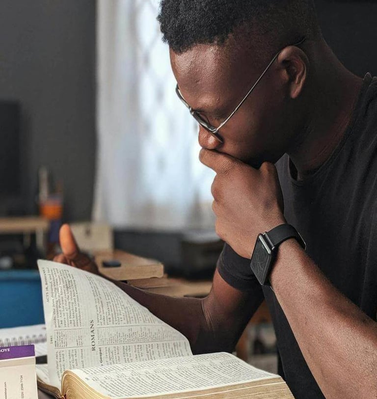 A man sitting at a desk with a bible and a laptop