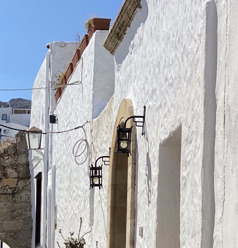 a man standing on a stone path in a narrow alley in Lindos village in Rhodes Greece
