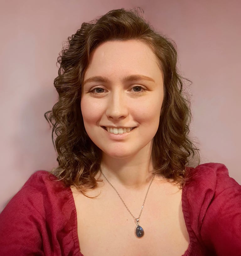 A photo of Katie Camm, the designer, smiling with a colorful backdrop