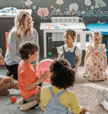 Happy children sitting in a circle, one with a large pink ball