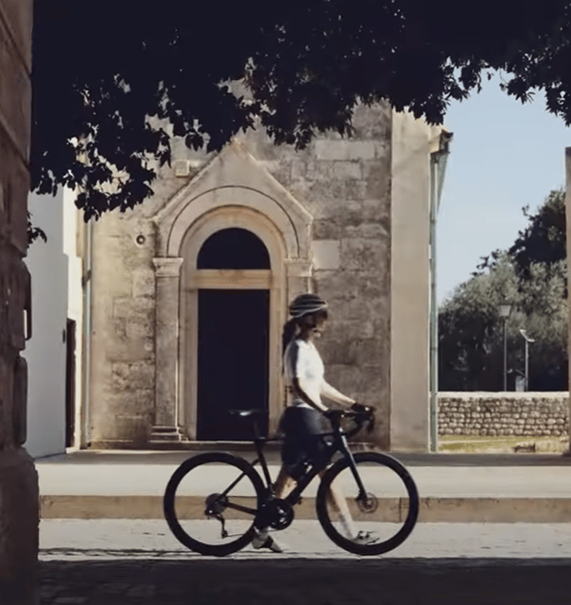 a woman riding a bicycle through a narrow alley