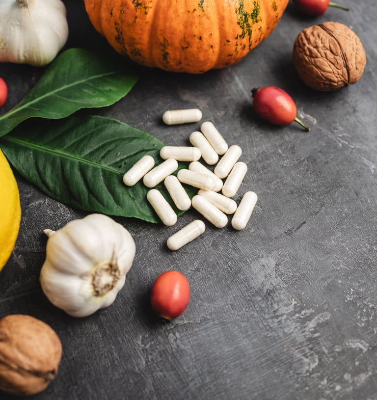 supplement pills, head of garlic, spinach leaf, lemon, and other fruits and vegetables on a table