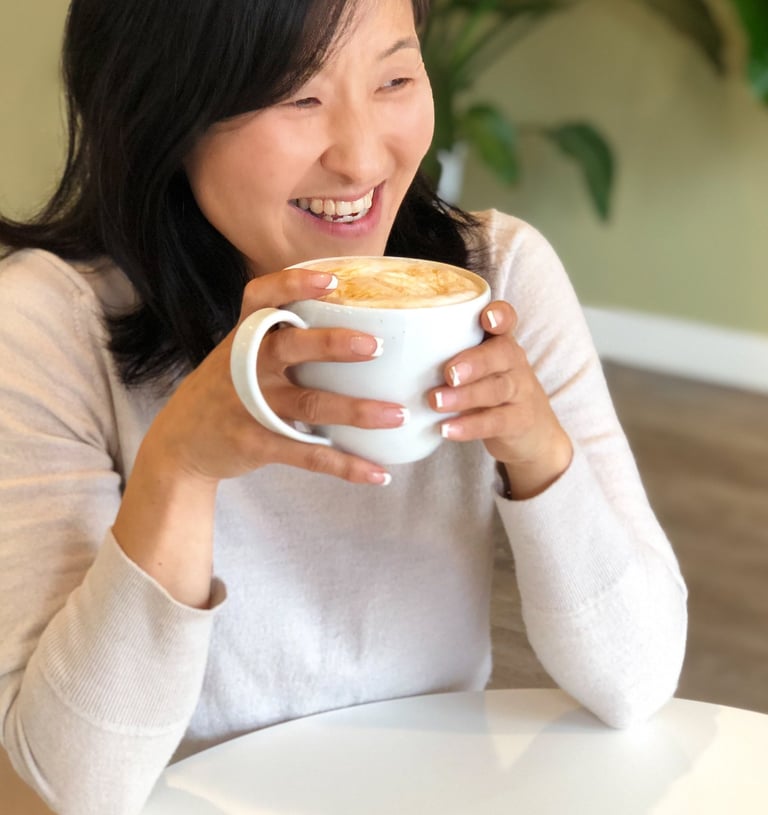 a woman is smiling and holding a cup of coffee