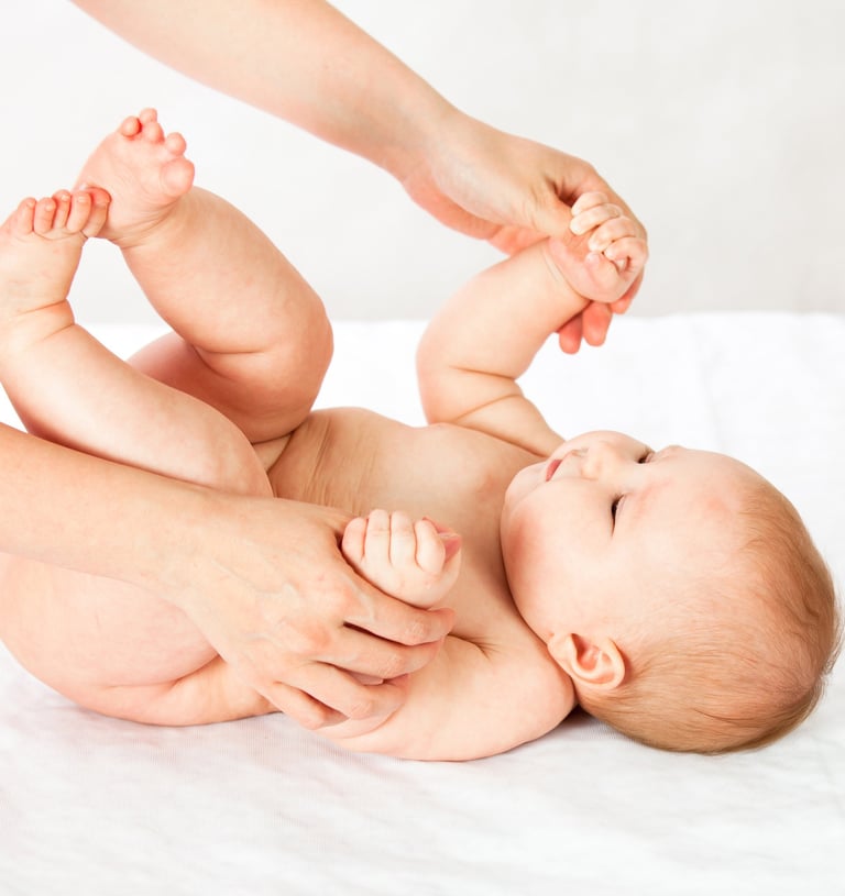 a baby is laying on a bed with a woman's hands