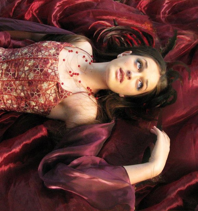 a woman in a red dress laying on a red blanket