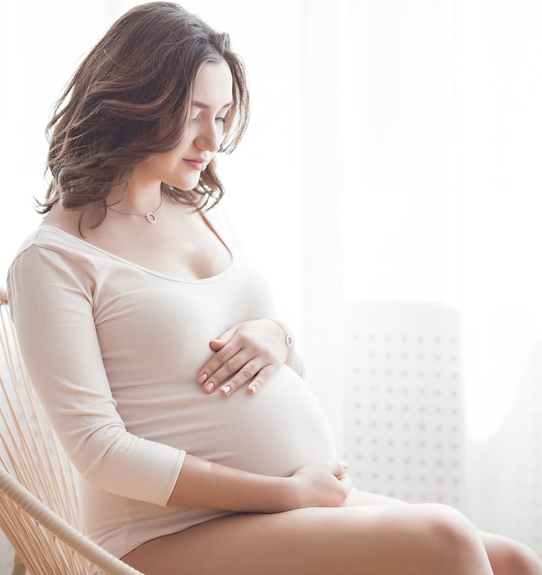 a pregnant woman sitting in a chair holding her belly