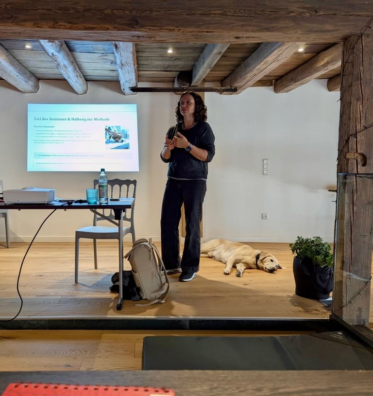 Svenja Stoll hält ein Seminar. Sie steht vor einer Präsentation und spricht zu den Teilnehmer:innen.