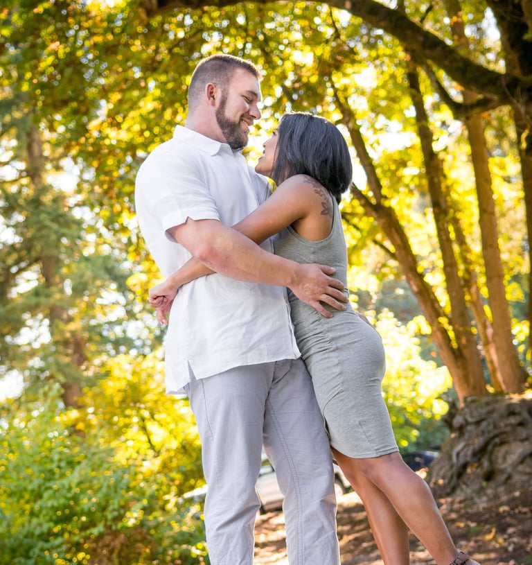 a man and woman standing in front of a tree
