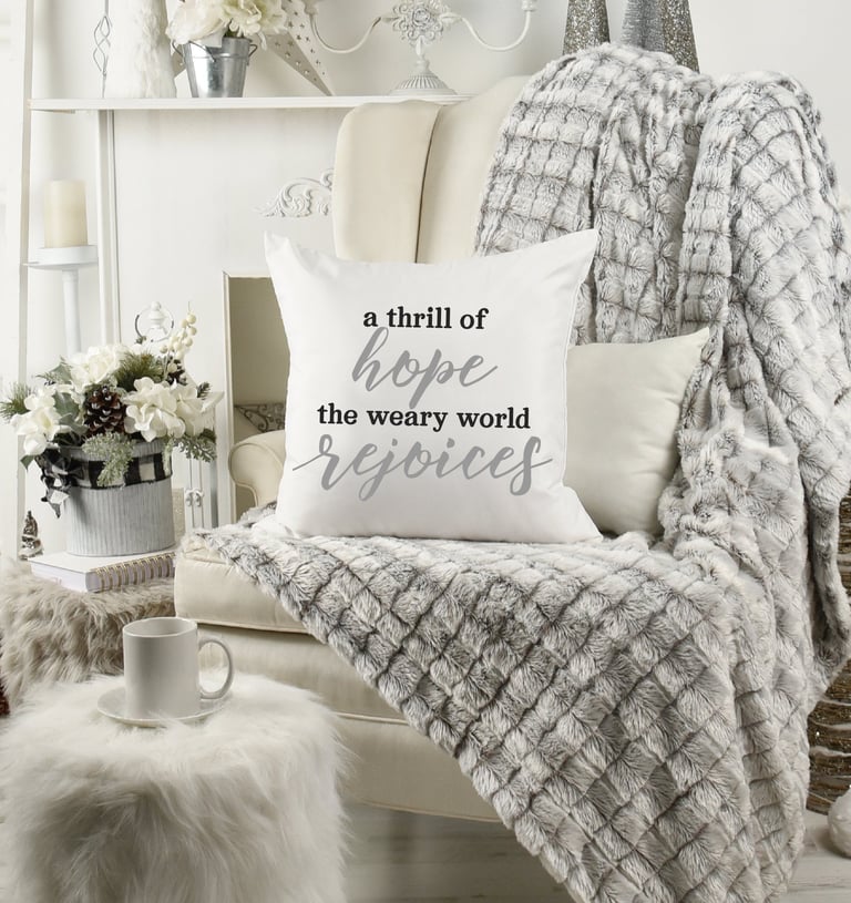 Cozy Christmas home with wing chair & fur throw. Coffee mug. Pillow reads "a thrill of hope the weary world rejoices."