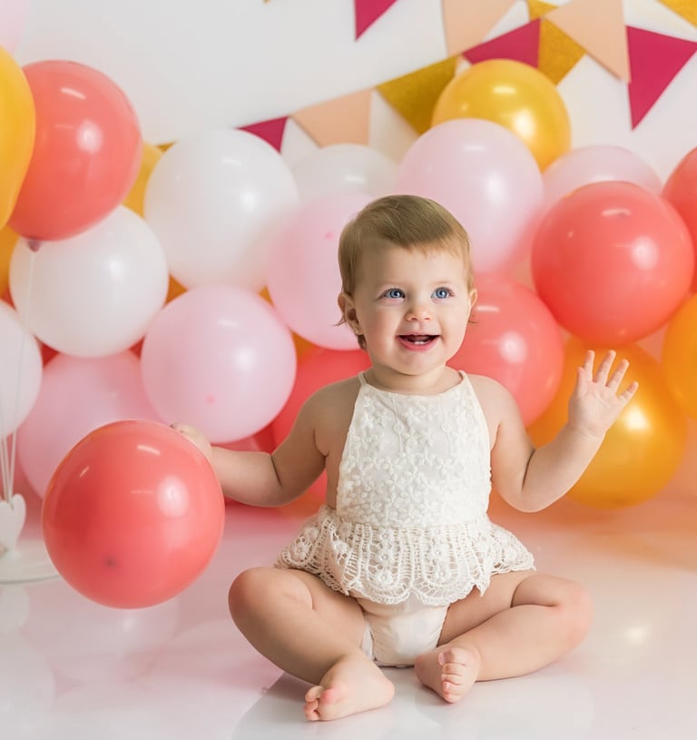 bebé sentada delante de globos en sesión de smash cake