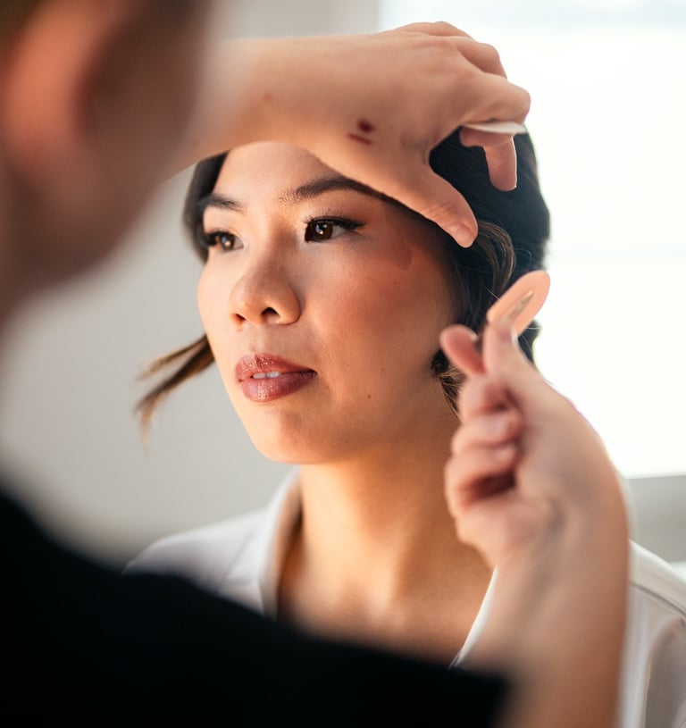 Maquilleuse ajustant les cheveux d’une mariée après le maquillage