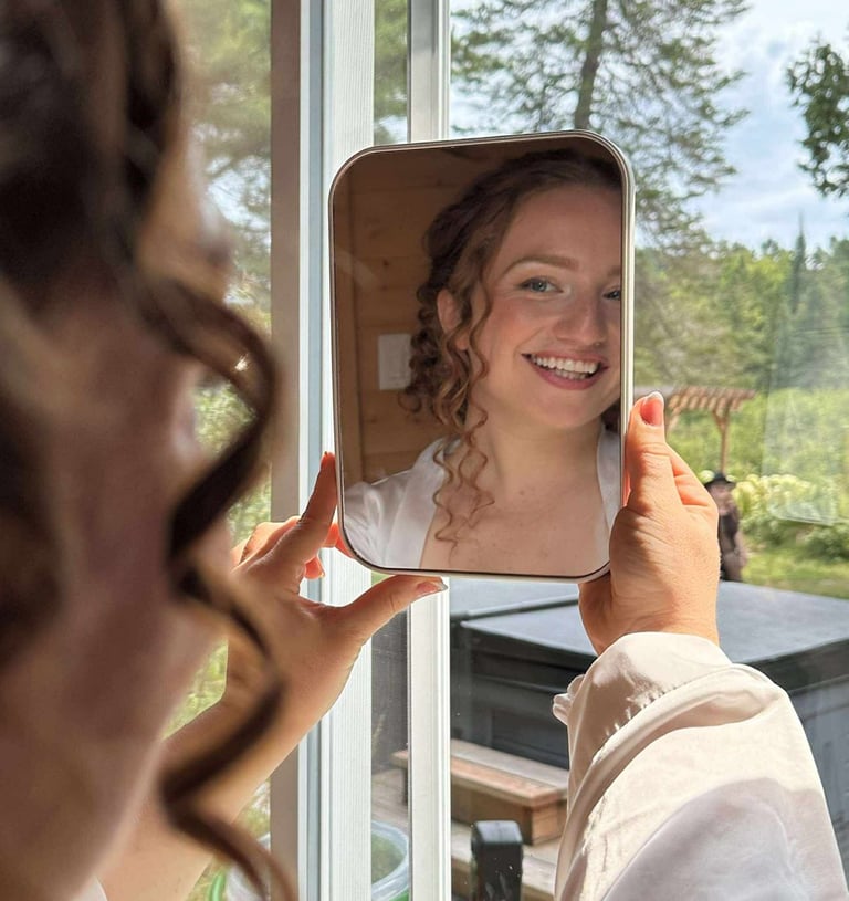 une mariée se regarde dans le miroir après son maquillage et sa coiffure et elle est heureuse