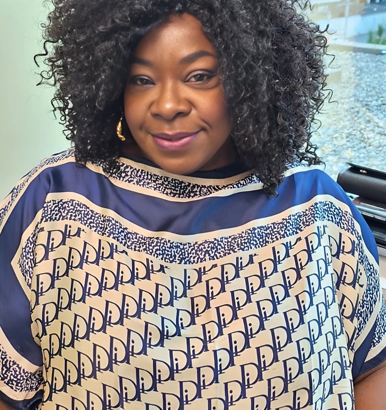 Smiling woman with voluminous curly hair wearing a blue and white patterned designer tunic top.