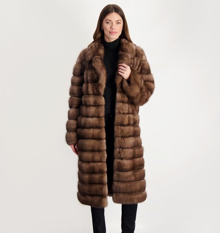 a woman in a long brown gorski coat with a fur coat