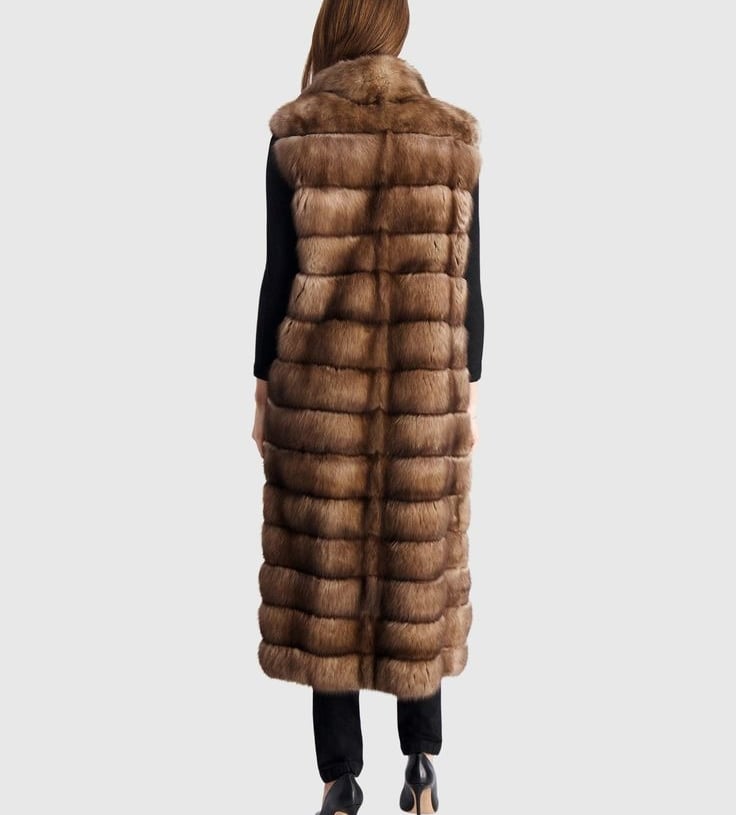 a woman wearing a long, brown gorski fur vest