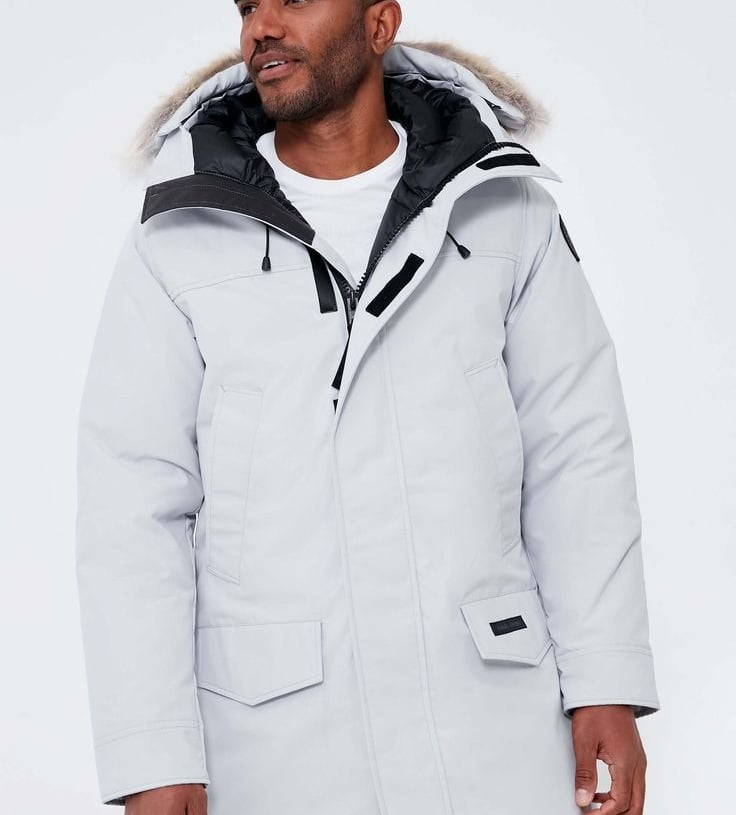 a man wearing a white jacket and grey pants