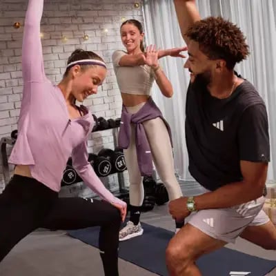 Diverse group of friends stretching and doing yoga lunges in a home gym setting with fitness gear.