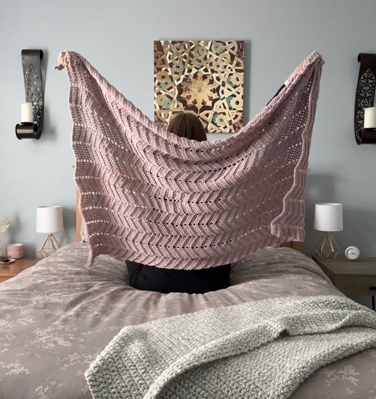 Owner of Beets & Stitches holding up purple crocheted throw blanket 