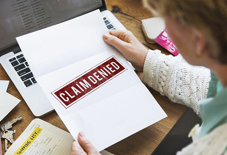 person looking at a denied insurance claim form