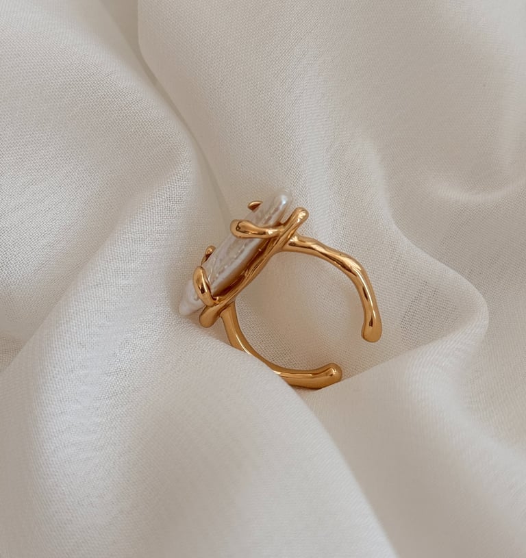 ein Ring mit einem perlenbesetzten Ring auf einem weißen Tuch