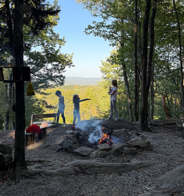 a group of children playing charades around a campfire with New Hampshire mountains beyond