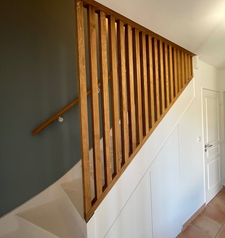 a staircase with a wooden handrail and a door