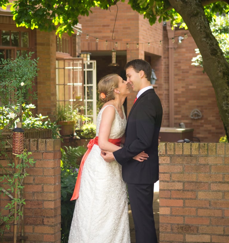 a bride and groom kissing in front of a brick wall
