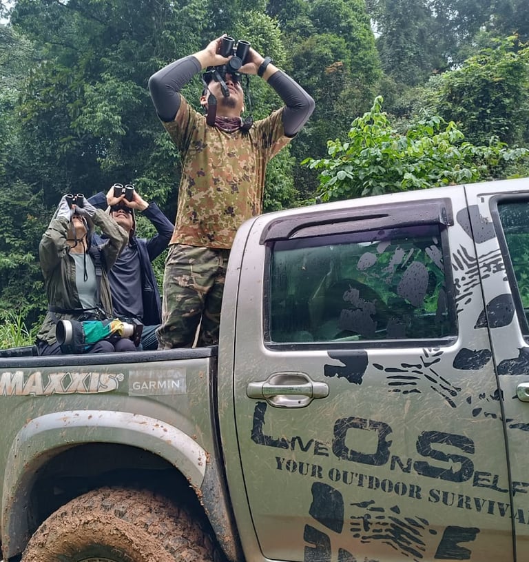 A guide in camouflage gear is observing the wildlife using the binocular 