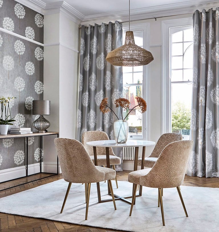 Modern dining room with gray dandelion wallpaper, round marble table, and beige velvet chairs.