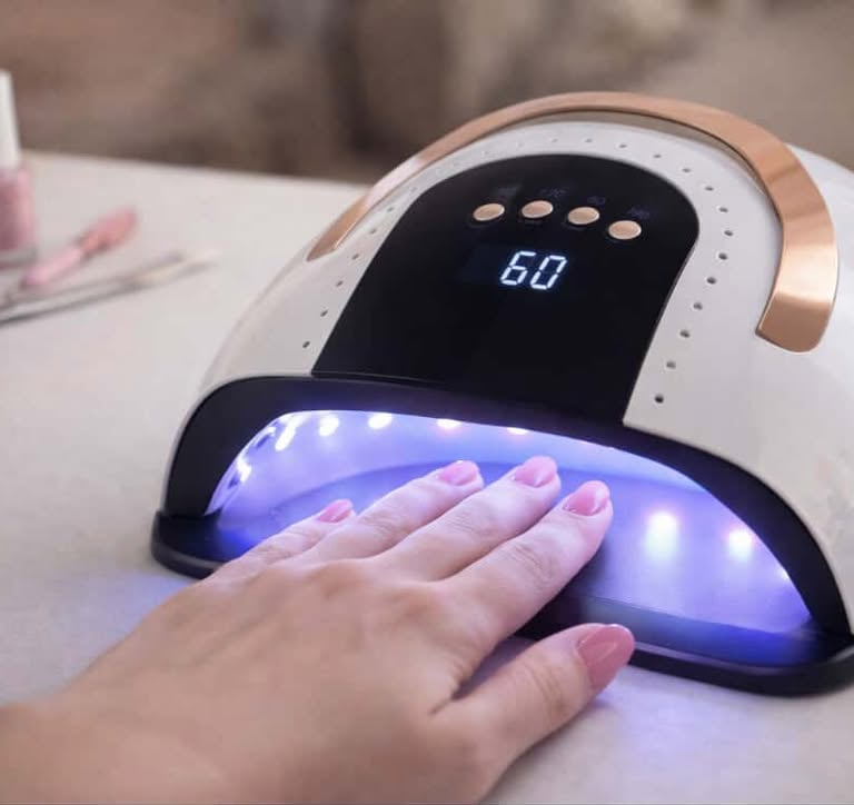 LED nail dryer curing gel polish on a hand during an at home manicure