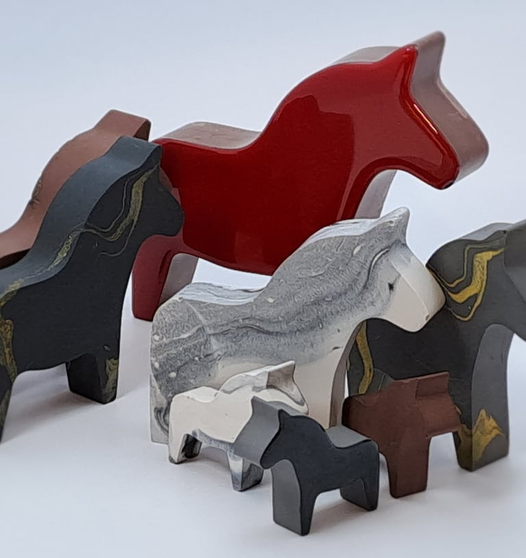 A collection of colorful handcrafted horse figurines in various sizes and colors.