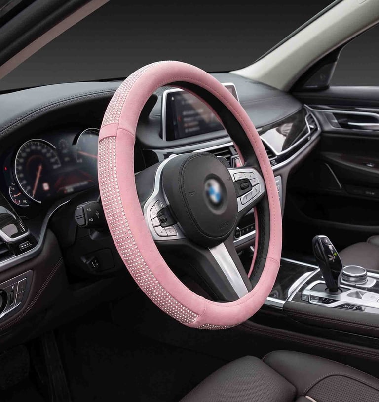 Sparkling pink rhinestone steering wheel cover installed in a luxury car interior with leather seats.