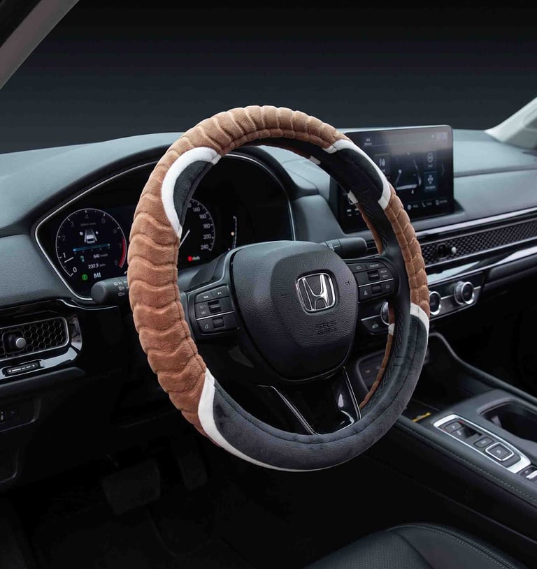 A brown and grey plush steering wheel cover installed on a black Honda dashboard.