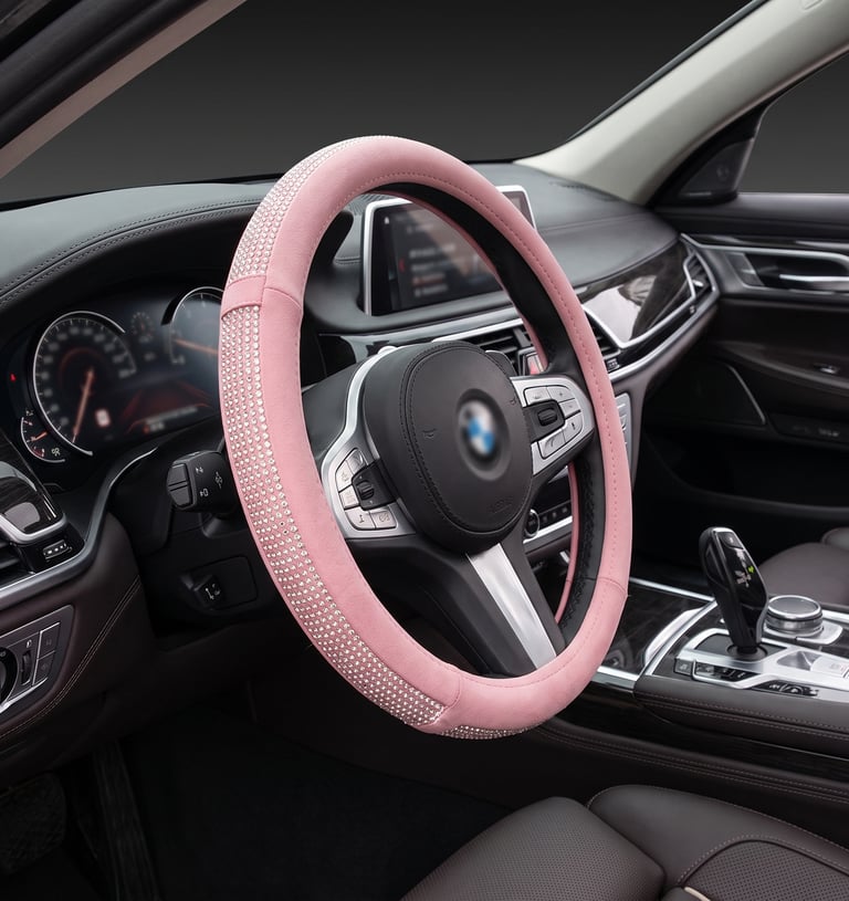 Luxury pink rhinestone steering wheel cover installed on a black leather car interior for a stylish sparkle.