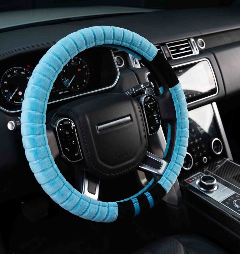 A light blue plush steering wheel cover installed on a black leather car interior for comfort and grip.
