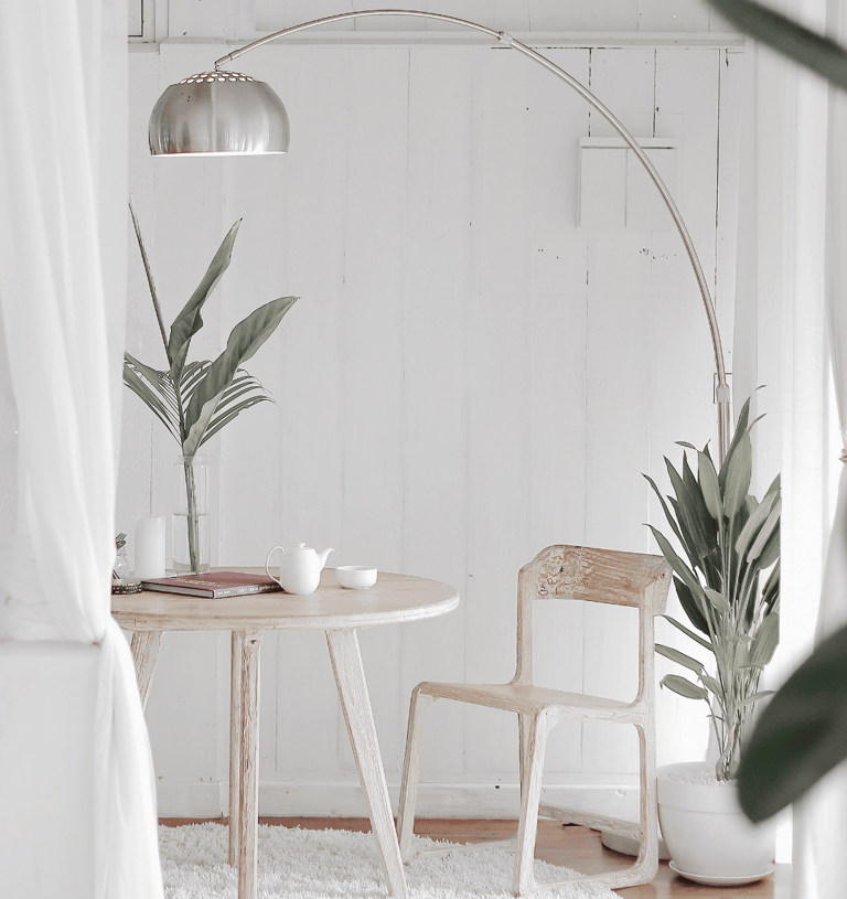 Small round table with a chair and indoor plants placed near a white wall.