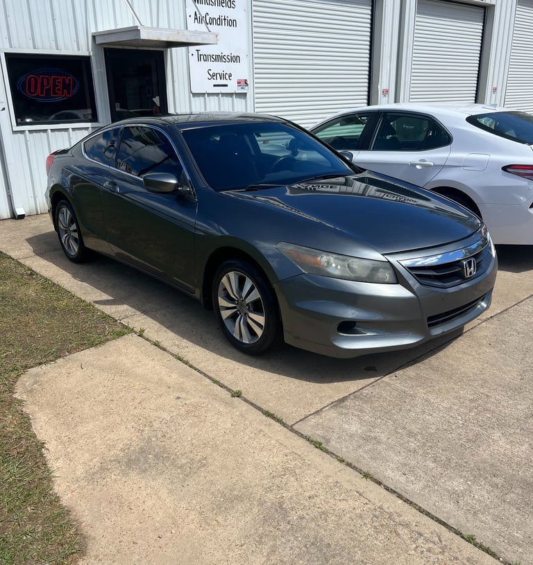 Dark gray Honda Accord coupe parked in front of an auto repair shop for transmission service and oil change.