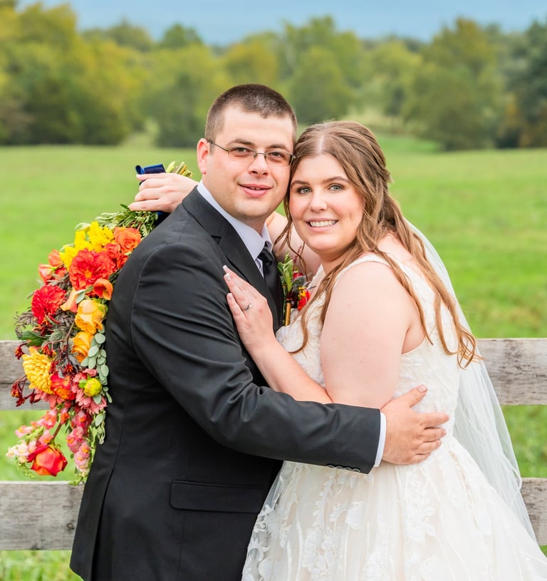a bride and groom standing in front of a fenced in area